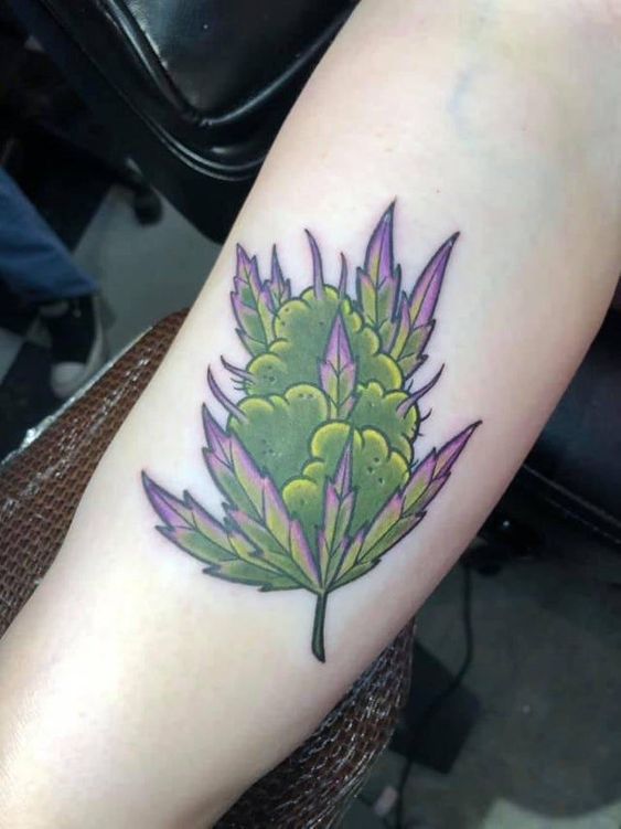 tatuagem de flor de maconha com tons roxos e verdes